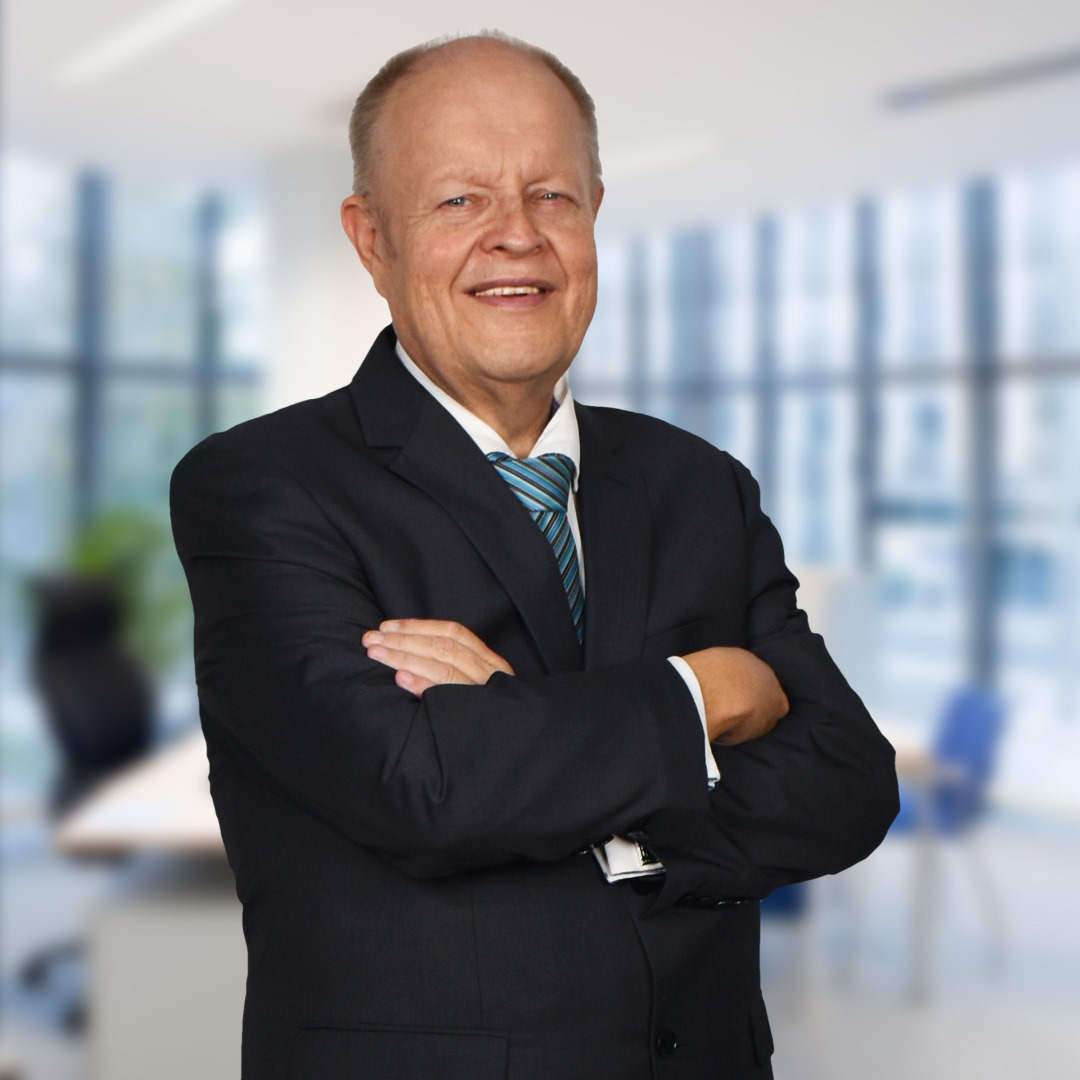 Senior business leader smiling with folded arms.